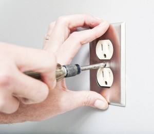 Hands installing electrical outlet cover plate.